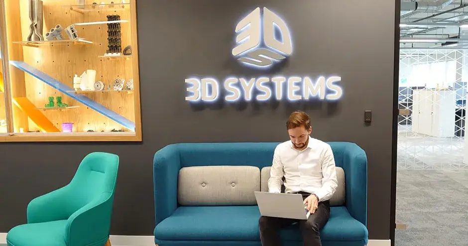 一个男人正坐在 3D Systems 休息室中使用笔记本电脑工作