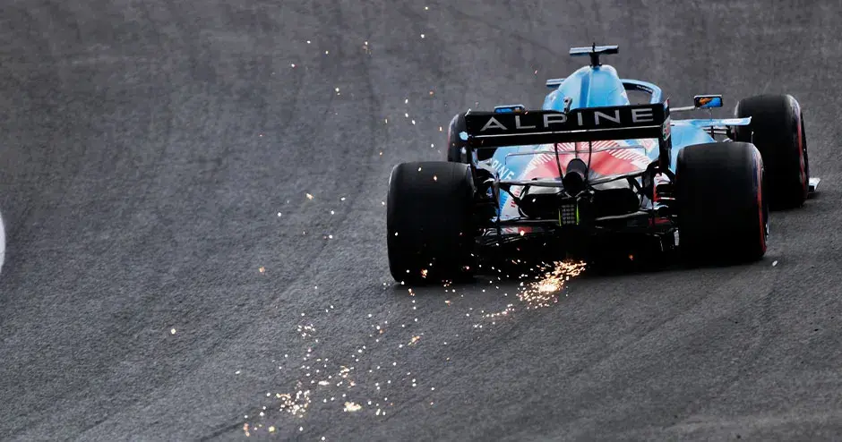 alpine f 1赛车在赛道上离去，车尾冒出火花